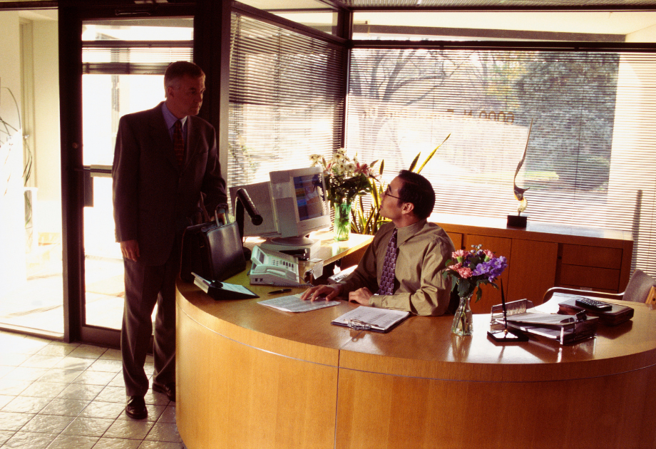 receptionist in an office talking to someone at the front desk